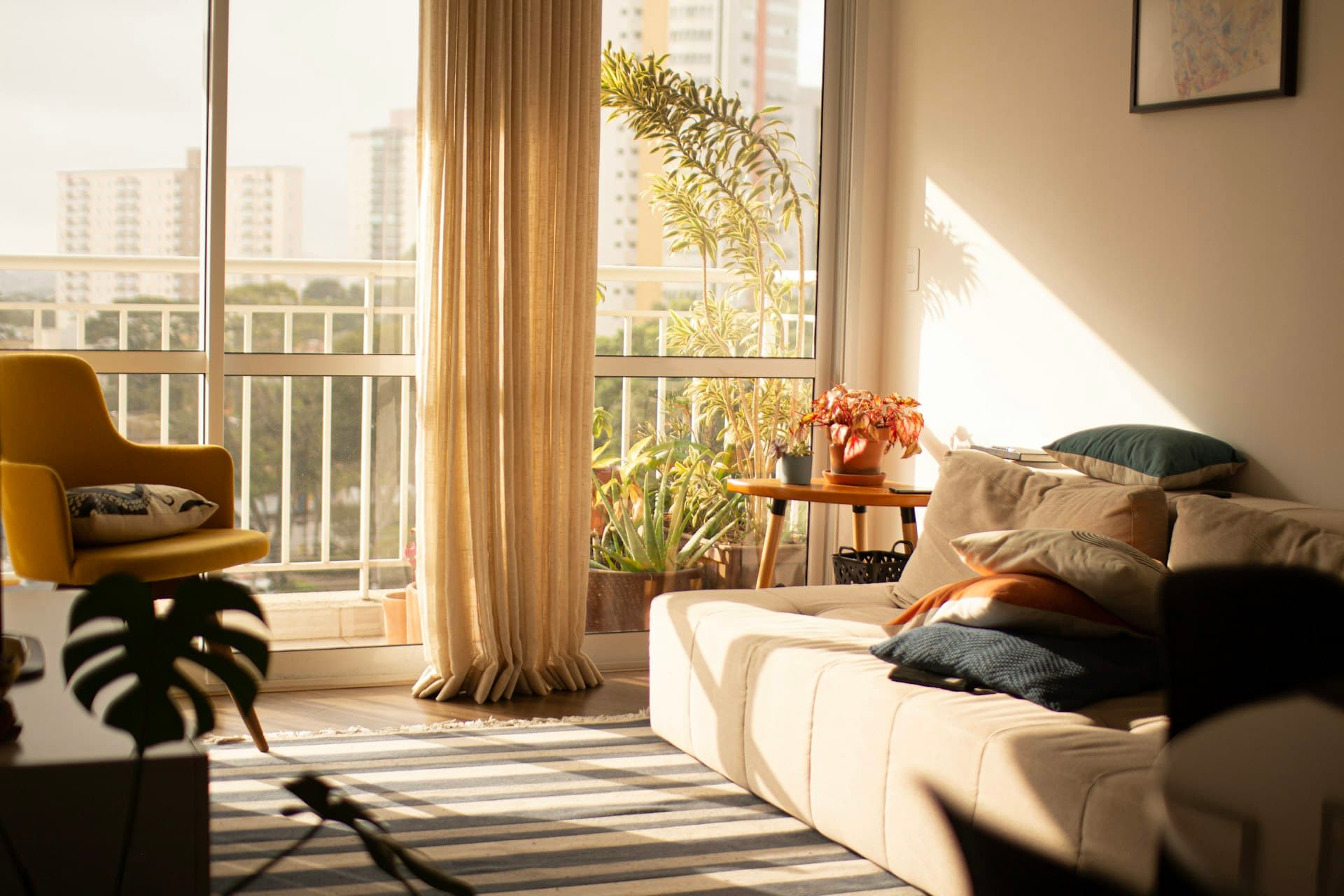 Helles Wohnzimmer einer Ferienwohnung mit großem Fenster und Pflanzen