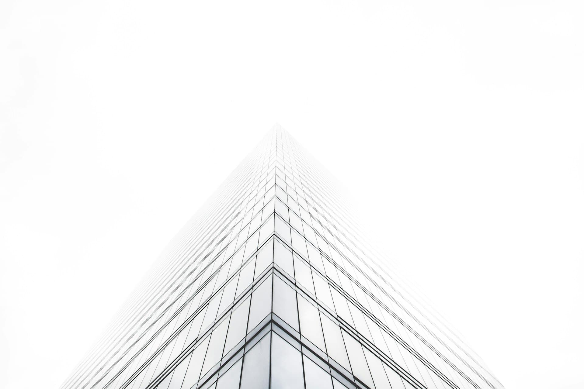 Glasfassade eines Hochhauses von unten, hell und geometrisch