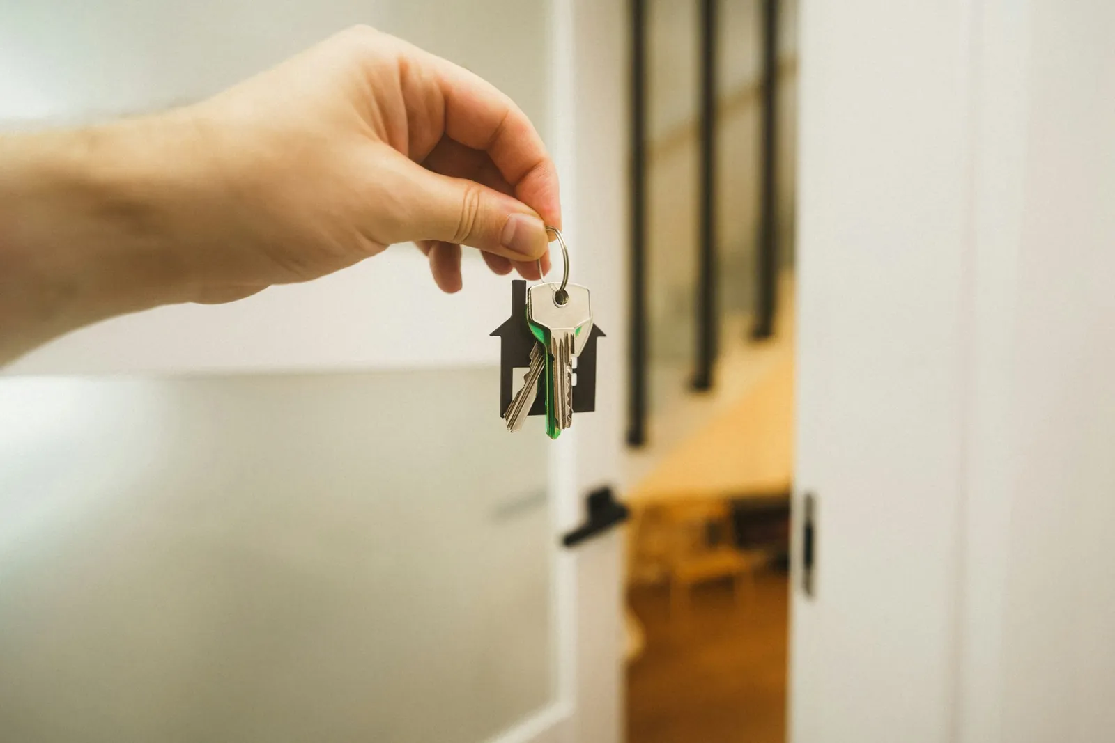 Hand hält einen Schlüssel an einer Wohnungstür