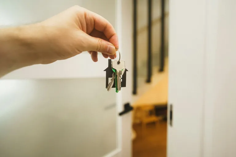 Hand hält einen Schlüssel an einer Wohnungstür