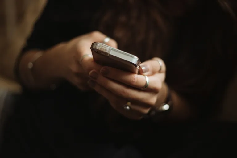 Person tippt am Abend eine Nachricht auf dem Smartphone