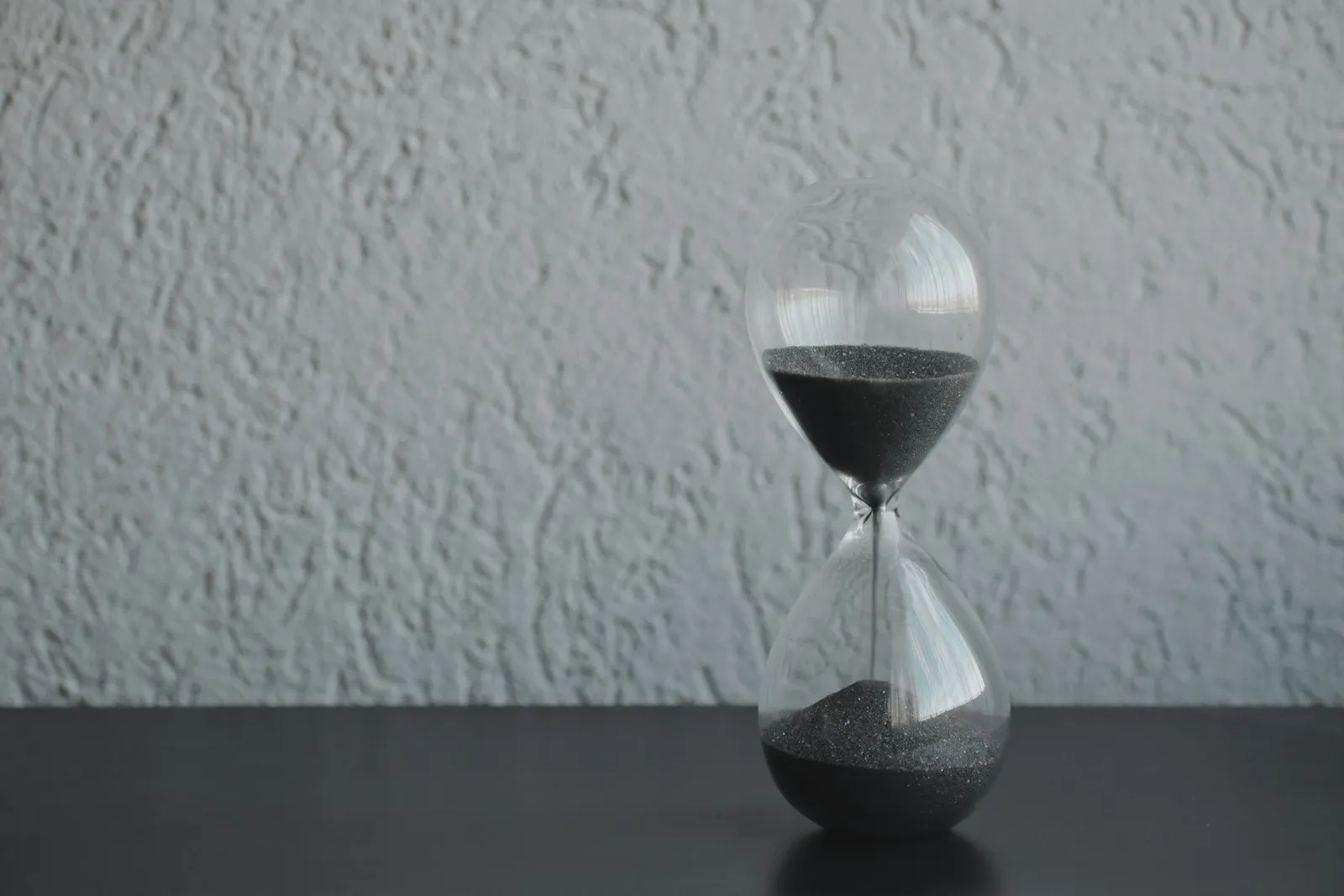 Sanduhr auf einem Tisch vor heller Wand