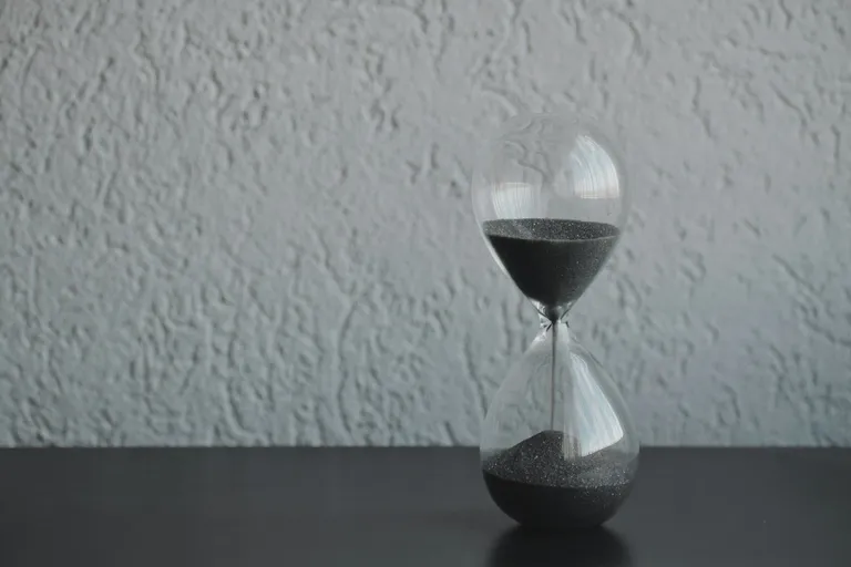 Sanduhr auf einem Tisch vor heller Wand