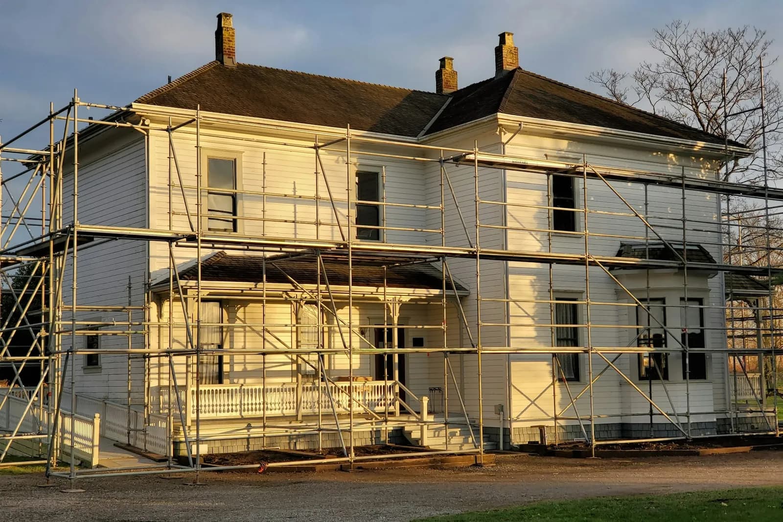 Weißes Holzhaus mit Baugerüst während der Renovierung