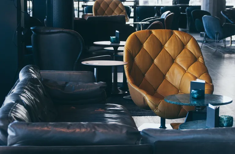 Leere Hotellobby mit hohen Fenstern und Sesselgruppe im Vormittagslicht