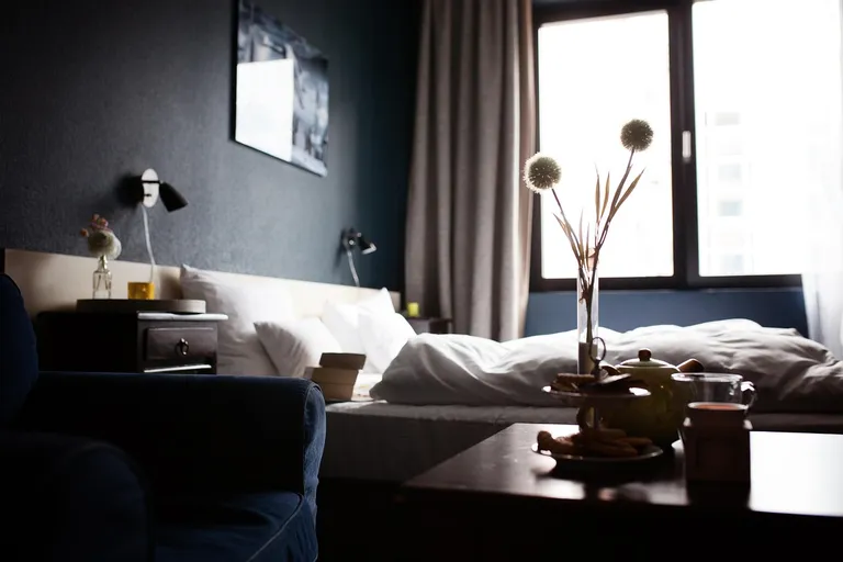 Hotelzimmer mit Leinenbettwäsche, Holzboden und offenem Fenster mit Bergblick