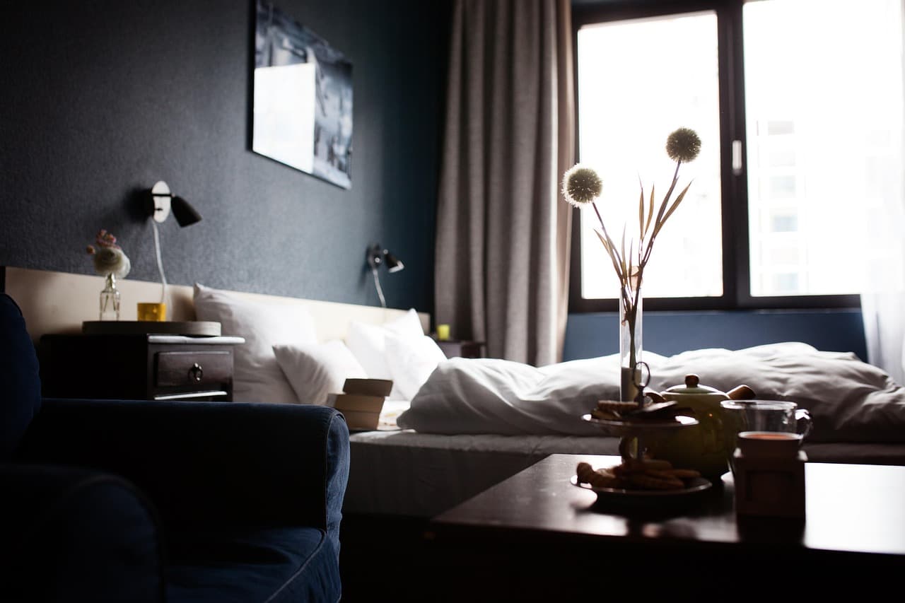 Hotelzimmer mit Leinenbettwäsche, Holzboden und offenem Fenster mit Bergblick